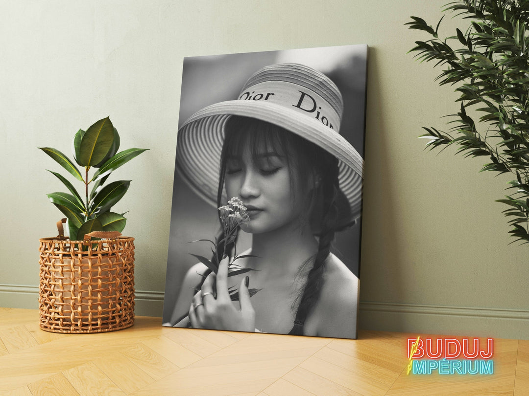Modern canvas print with a black and white portrait of a woman in a hat holding a flower in a modern interior