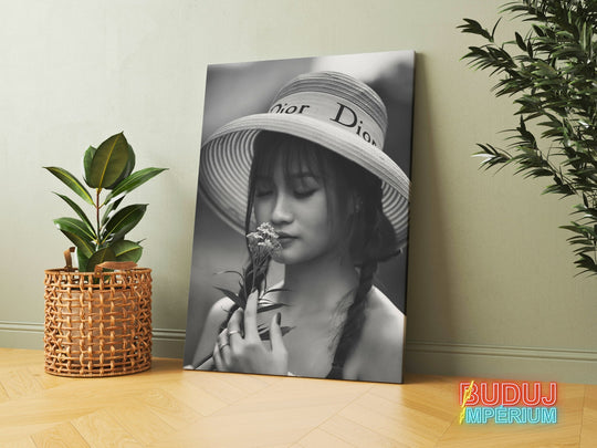 Modern canvas print with a black and white portrait of a woman in a hat holding a flower in a modern interior