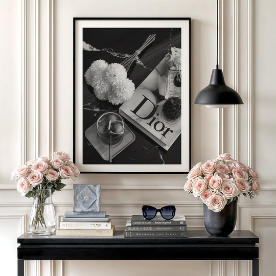 Modern wall art in an elegant living room with a black and white photo of a table with coffee, flowers and a Dior book.