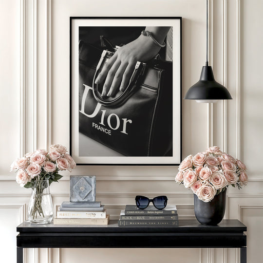 Luxury wall art with a black and white photograph of a Dior handbag in hand in a minimalist interior, fashion decor