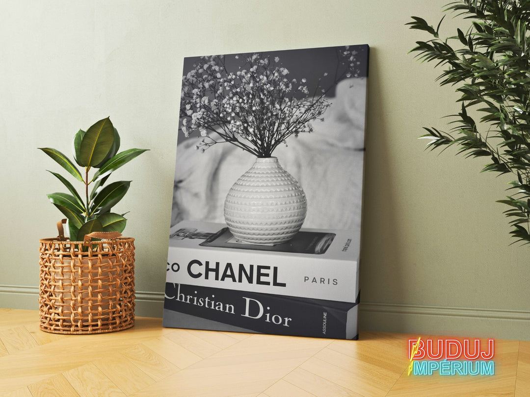 Luxury canvas print with black and white Chanel and Christian Dior book spines and a vase with dried flowers in an interior