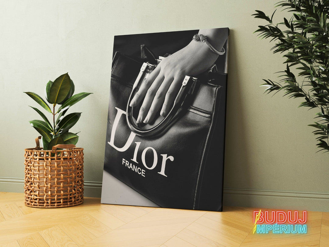 Modern canvas print with a black and white photo of a Dior handbag and a woman’s hand, leaning against a wall between houseplants