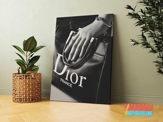 Modern canvas print with a black and white photo of a Dior handbag and a woman’s hand, leaning against a wall between houseplants