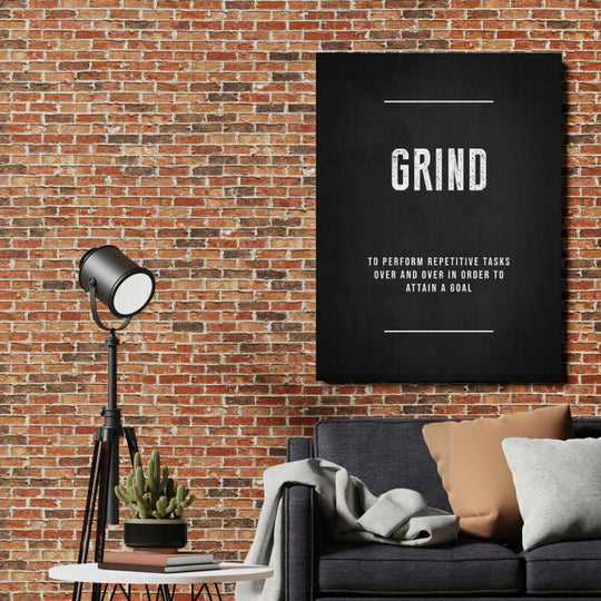 GRIND motivational wall art with a definition quote hanging on a brick wall in an industrial living room.