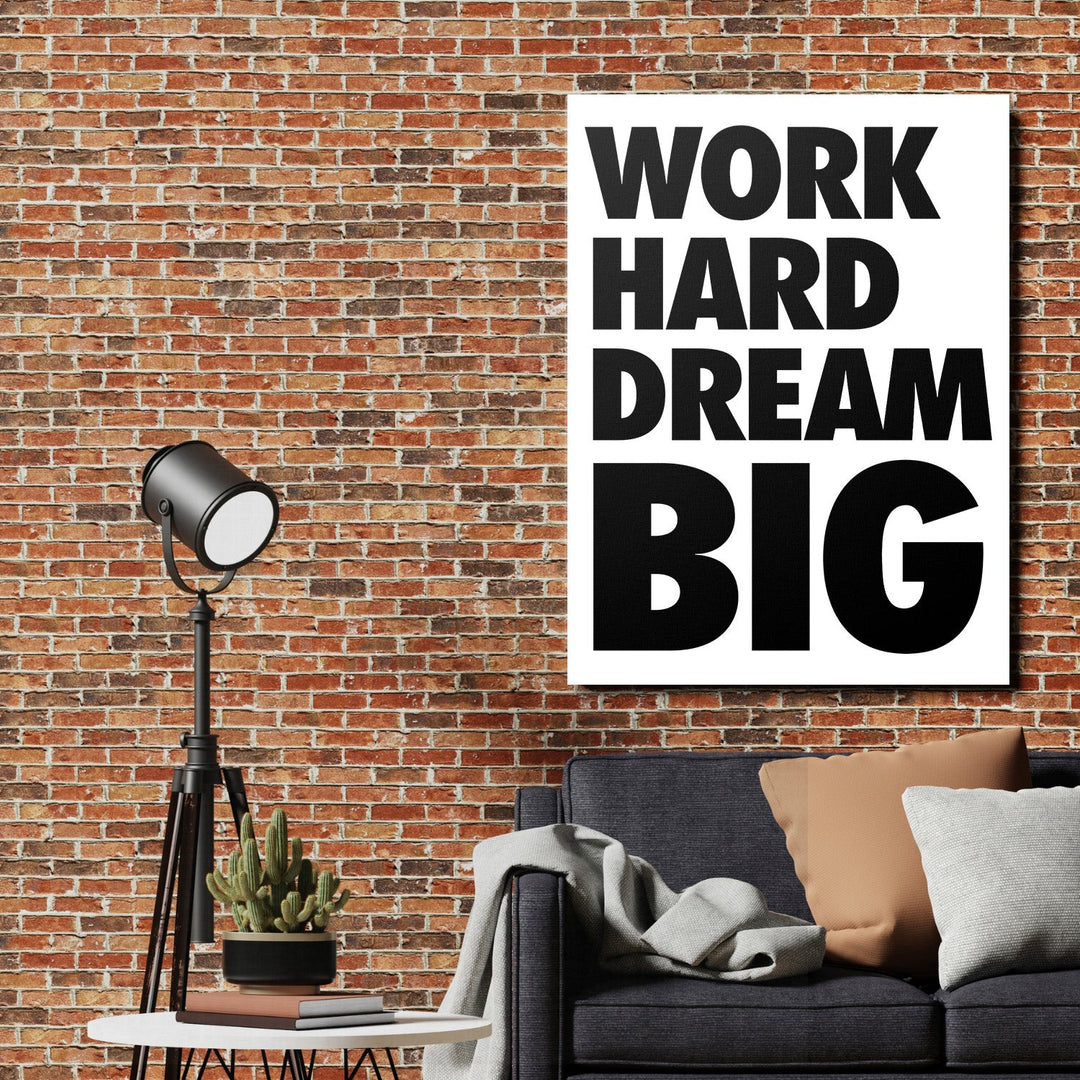 WORK HARD DREAM BIG motivational canvas wall art in an industrial interior above a dark gray sofa