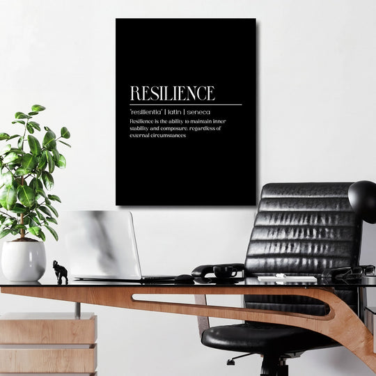 Motivational wall art with a black-and-white Latin Resilience quote above a desk in a modern office