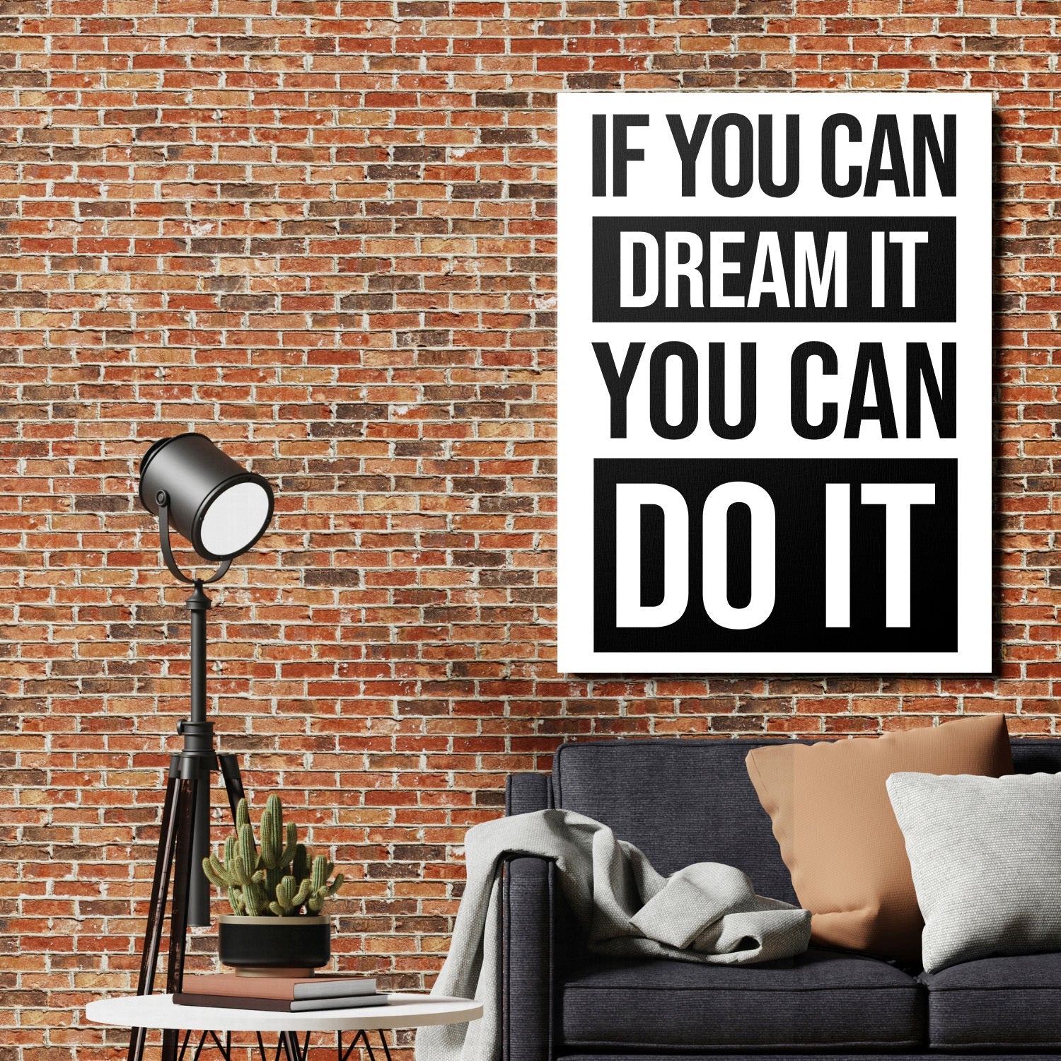 Black and white motivational quote wall art above a sofa beside a brick wall and floor lamp