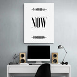 Motivational wall art for a modern office with a minimalist black-and-white “Now” quote above a desk.
