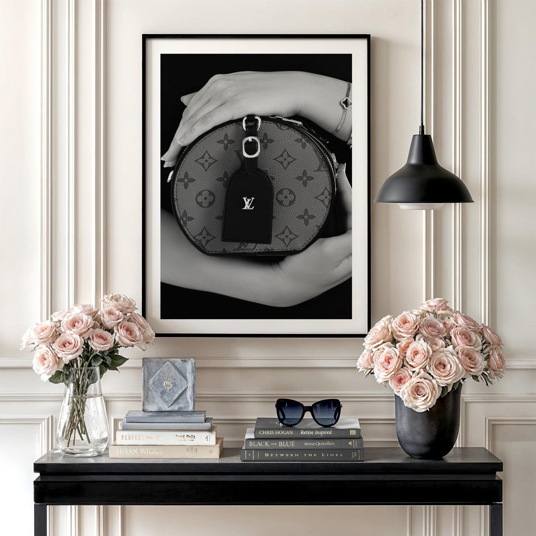 Modern wall art with a black and white photograph of a luxury handbag in an interior above fresh flowers