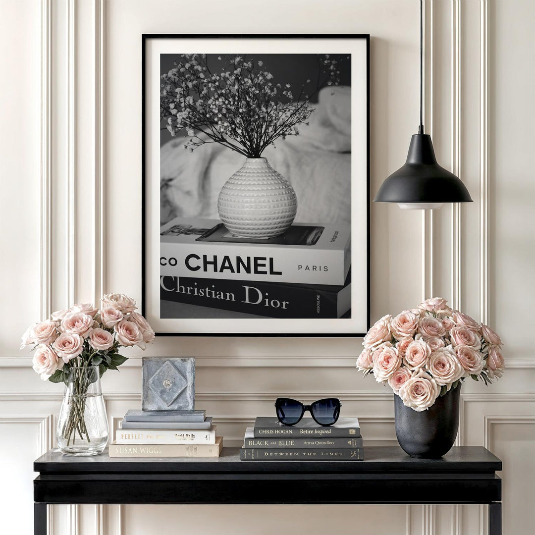 Modern wall art with a black and white photograph of a vase on Chanel and Dior books in a living room