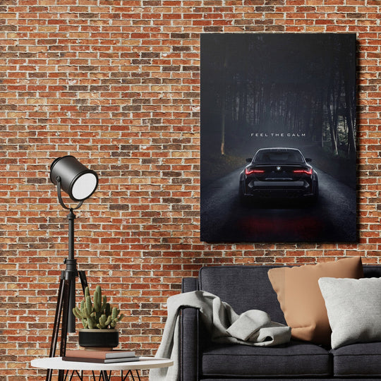 Motivational canvas print with a black BMW on a dark forest road and the quote “Feel the Calm” in a living room
