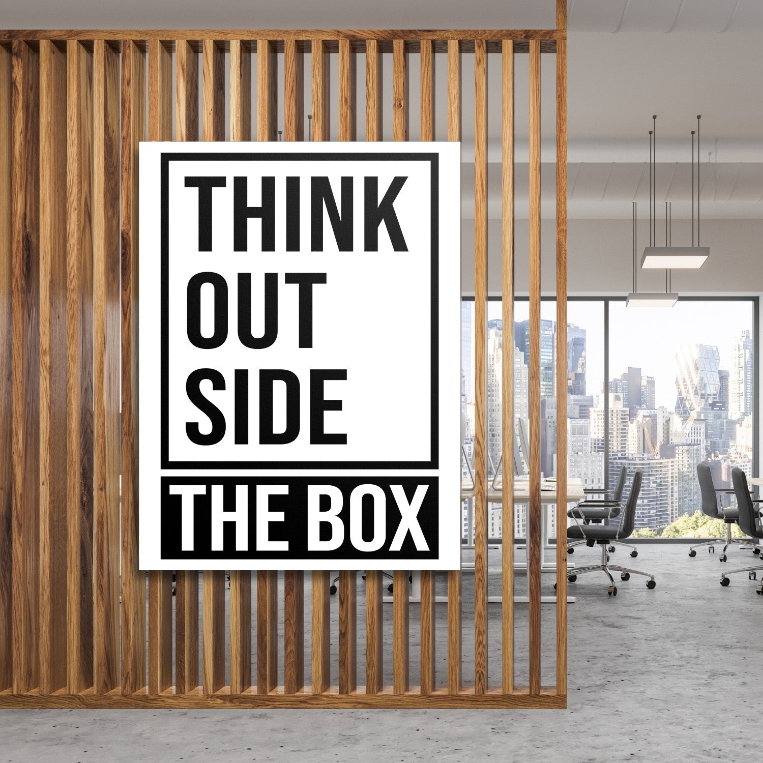 Motivational canvas print with a “Think outside the box” quote in a modern office behind a wooden partition