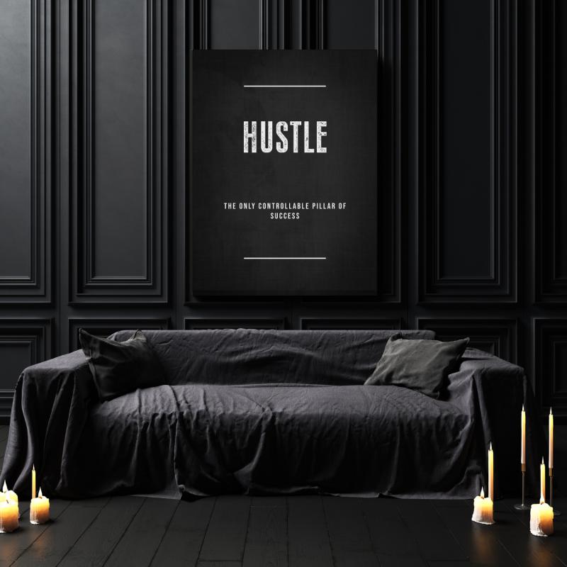 HUSTLE motivational canvas print in a dark interior above a black sofa and burning candles.