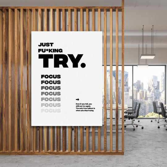 Black and white “Just Fu*king Try. Focus…” motivational canvas print hanging in a modern office.