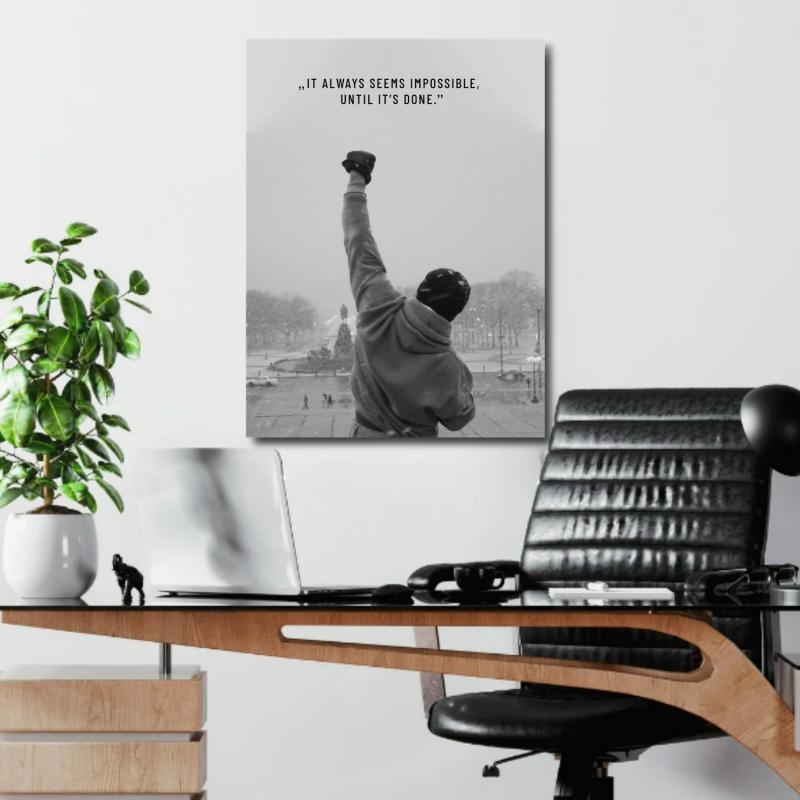 Motivational wall art for an office with a black and white fist, quote and green plant in the background.