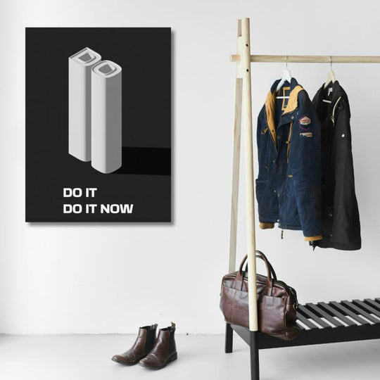 Motivational canvas print with a 3D quote on a white wall next to a coat rack with jackets and shoes.