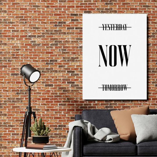 Motivational wall art with NOW text and crossed-out Yesterday and Tomorrow on an industrial brick wall.
